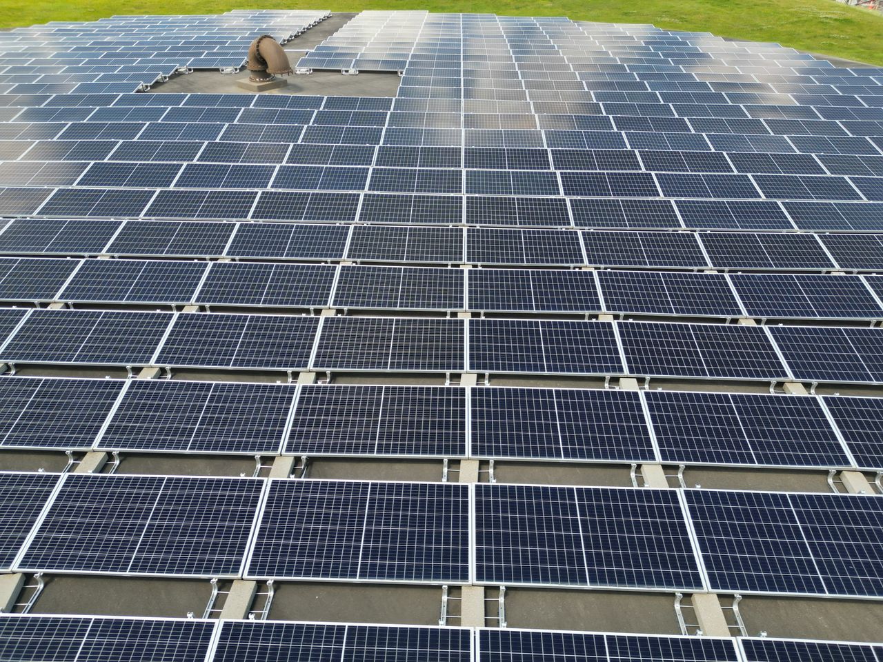 why-choose-us-02 A large solar panel array on a sunny day in an open green field.